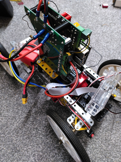 A Meccano model car with a Raspberry Pi on top and the shiny red gearbox in the middle