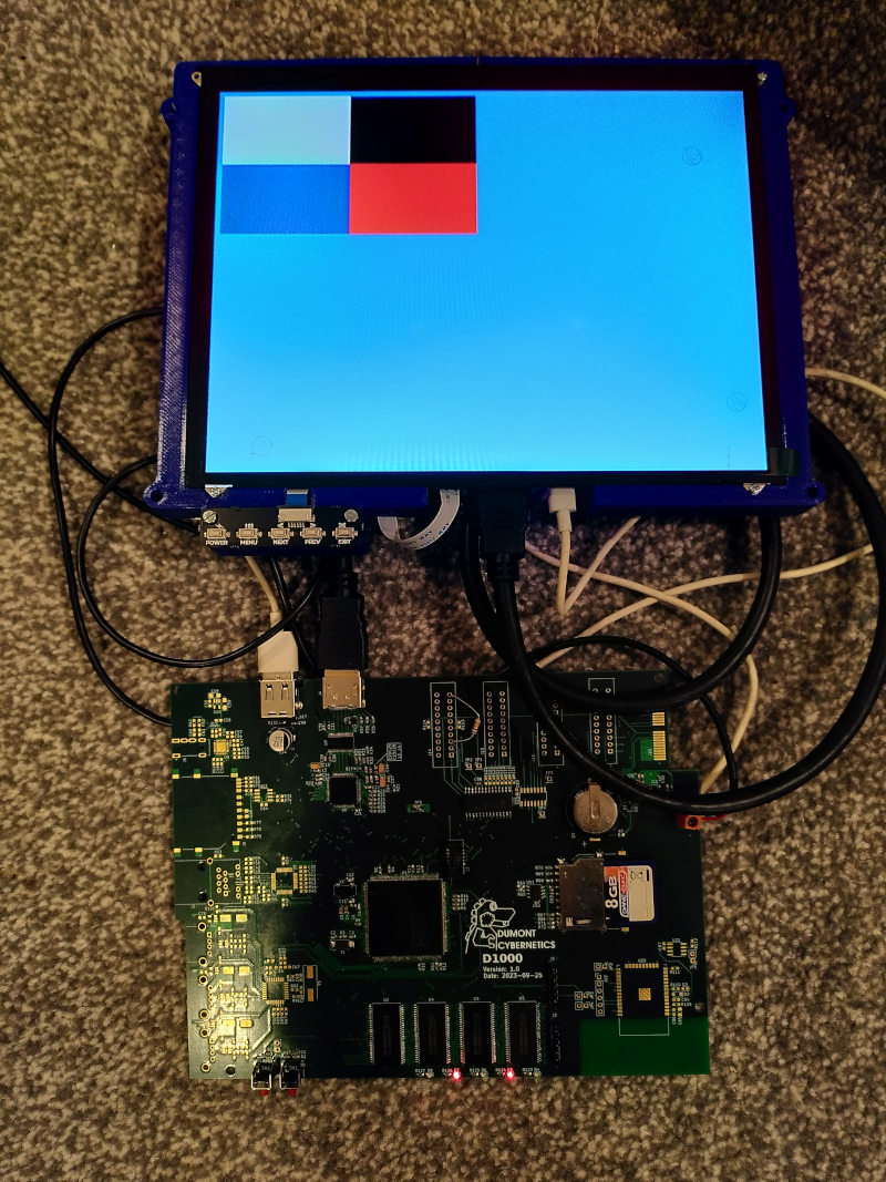 A small computer display showing a test pattern of red, white, black and red in a screen of blue next to a partly populated circuit board.